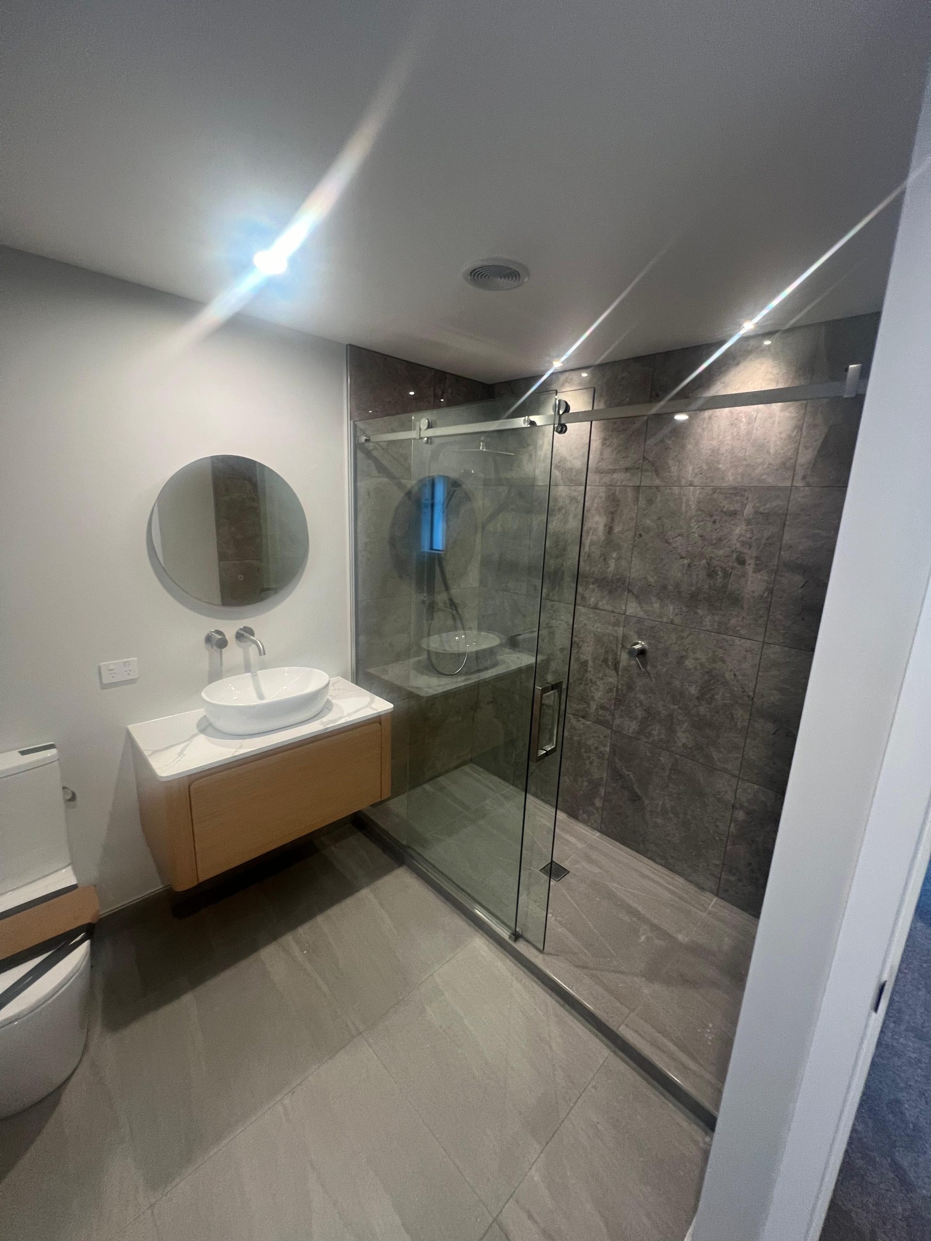 a bathroom with a glass shower door RNF Construction